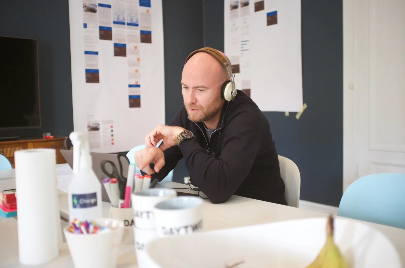 Daytwo-ansatt med hodetelefoner arbeider konsentrert ved skrivebord med post-it-lapper på veggen – arbeidsmiljø i kreativt digitalt byrå